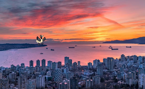 An aerial view of Vancouver with a red orange sunset looking over downtown and Burrard Inlet towards the UBC Peninsula